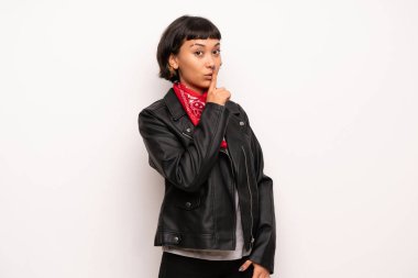 Deri ceket ve mendil bir işaret parmağını ağzına koyarak sessizlik jest gösteren kadın ile