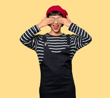 Gözleri eller tarafından kapsayan bere olan kadın. Sarı arka plan üzerinde ileride ne gördüğüme şaşırdım