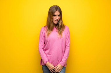 Kadın üzgün ve depresyonda ifade ile sarı duvarın üzerinden pembe kazak