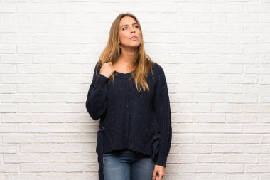 Yorgun ve hasta ifade ile tuğla duvarın üzerinden sarışın kadın