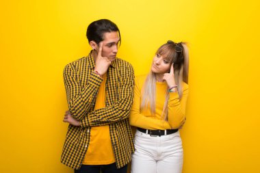 Şüpheler ve düşünme sahip canlı sarı arka plan üzerinde Genç çift