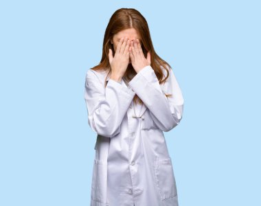 Kızıl saçlı doktor kadın yorgun ve hasta ifade izole mavi arka plan ile