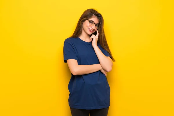 Sarı Duvarın Önüne Bakarak Üzerinden Gözlüklü Genç Kadın — Stok fotoğraf