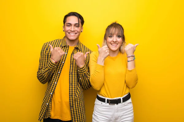 Junges Paar Auf Leuchtend Gelbem Hintergrund Das Mit Beiden Händen — Stockfoto