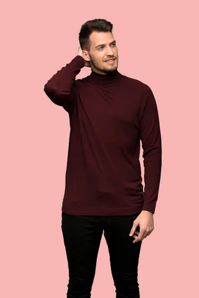 Man with turtleneck sweater thinking an idea while scratching head over pink background