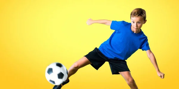 Menino Jogando Futebol Chutando Bola Fundo Amarelo — Fotografia de Stock