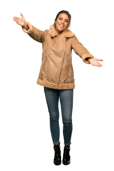 提示し 分離の白い背景の上の手が付属する招待のコートと金髪女性のフルレングス ショット — ストック写真