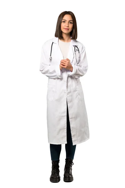 一个年轻的医生妇女笑着看着前面在孤立的白色背景的全长镜头 — 图库照片