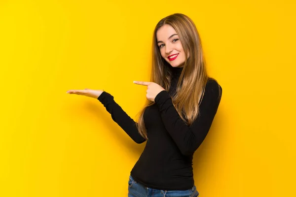 Joven Mujer Bonita Sobre Fondo Amarillo Sosteniendo Espacio Copia Imaginario —  Fotos de Stock