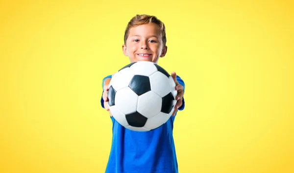 Αγόρι Παίζει Ποδόσφαιρο Κίτρινο Φόντο — Φωτογραφία Αρχείου