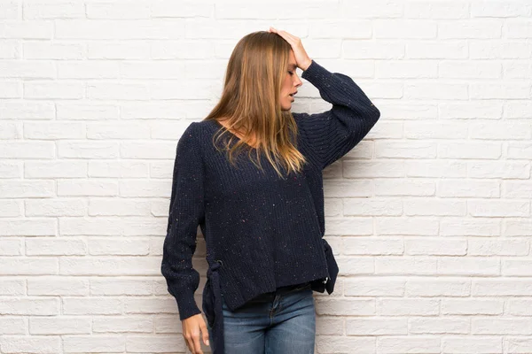 Blonde woman over brick wall intending to realizes the solution while lifting a finger up