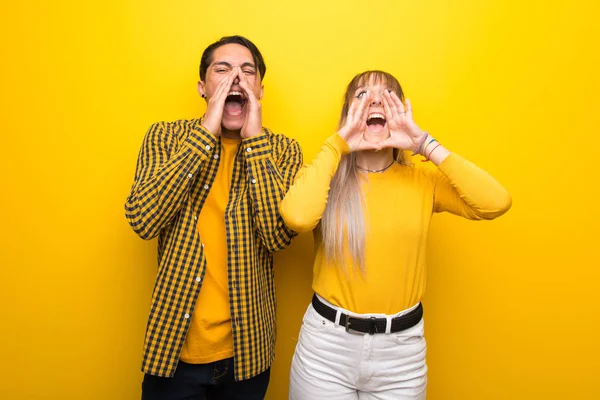Junges Paar Vor Leuchtend Gelbem Hintergrund Schreit Und Kündigt Etwas — Stockfoto