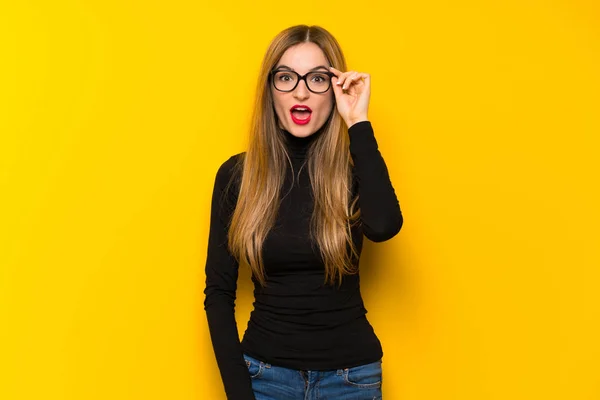 Joven Bonita Mujer Sobre Fondo Amarillo Con Gafas Sorprendida — Foto de Stock