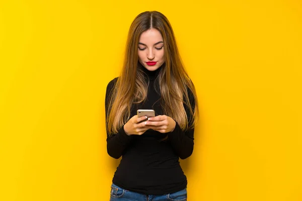 Mujer Bonita Joven Sobre Fondo Amarillo Enviando Mensaje Con Móvil —  Fotos de Stock