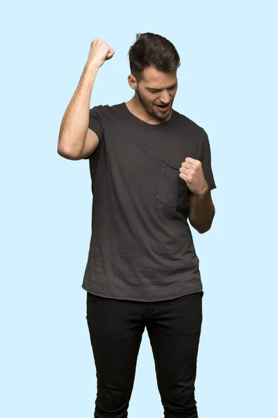 Adam Siyah Gömleği Mavi Arka Plan Üzerinde Bir Zafer Kutluyor — Stok fotoğraf