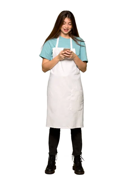 Полнометражный Снимок Девочки Фартуке Отправляющей Сообщение Мобильного Изолированном Белом Фоне — стоковое фото