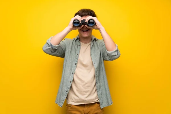 Hombre Adolescente Sobre Pared Amarilla Mirando Distancia Con Prismáticos — Foto de Stock