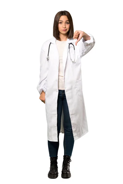 一个年轻医生的妇女在孤立的白色背景上显示拇指下垂与负面表情的全长照片 — 图库照片