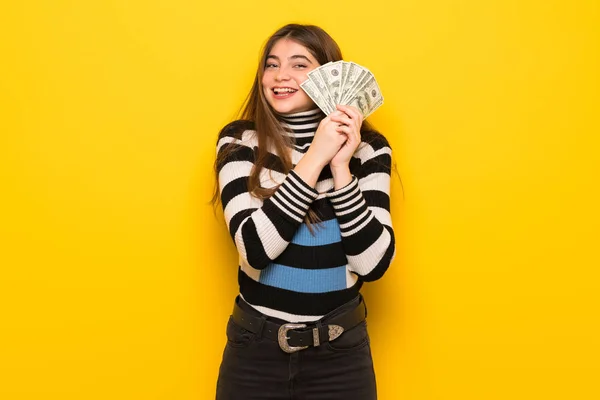 Joven Mujer Sobre Pared Amarilla Tomando Montón Dinero —  Fotos de Stock