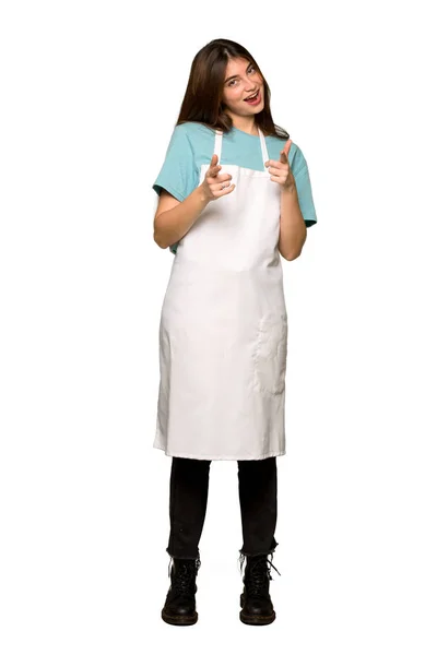 Full-length shot of Girl with apron pointing to the front and smiling on isolated white background