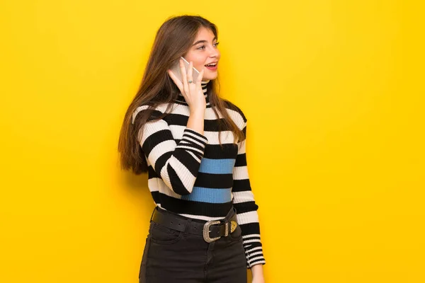 Молода Жінка Над Жовтою Стіною Тримає Розмову Мобільним Телефоном — стокове фото