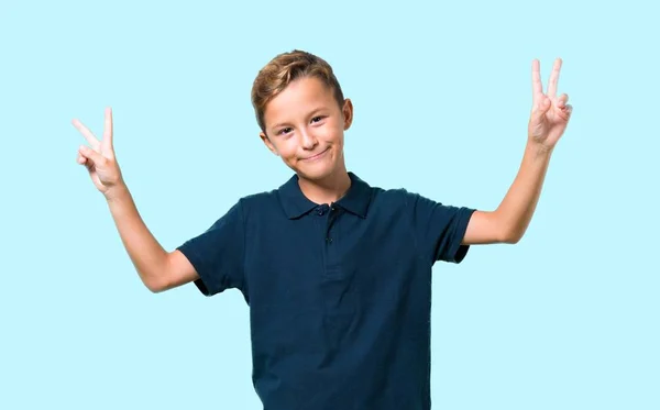 Menino Sorrindo Mostrando Sinal Vitória Fundo Azul — Fotografia de Stock