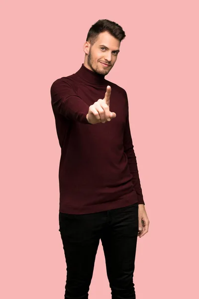 タートルネックのセーターを示すと ピンクの背景の上の指を離すと男 — ストック写真