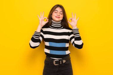 Genç kadın zen sarı duvarın üzerinden poz