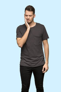 Adam siyah gömlek ile mavi arka plan üzerinde diş ağrısı ile