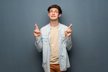 Jean ceket gri duvar ile en iyi dilek ve geçiş parmak üzerinde olan genç adam