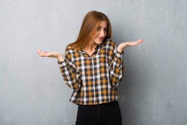 Genç Kızıl saçlı kız omuz kaldırma sırasında önemli jest yapma grunge duvarın üzerinden