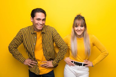 Canlı sarı arka plan üzerinde genç çift mutlu ve gülümseyen