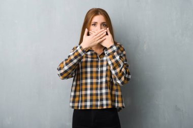 Uygunsuz bir şey söylediğin için el ile ağız kapsayan grunge duvarın üzerinden genç Kızıl saçlı kız