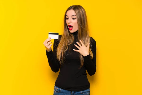 Joven Bonita Mujer Sobre Fondo Amarillo Sosteniendo Una Tarjeta Crédito —  Fotos de Stock