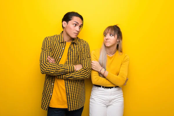Junges Paar Vor Leuchtend Gelbem Hintergrund Macht Zweifel Geste Beim — Stockfoto