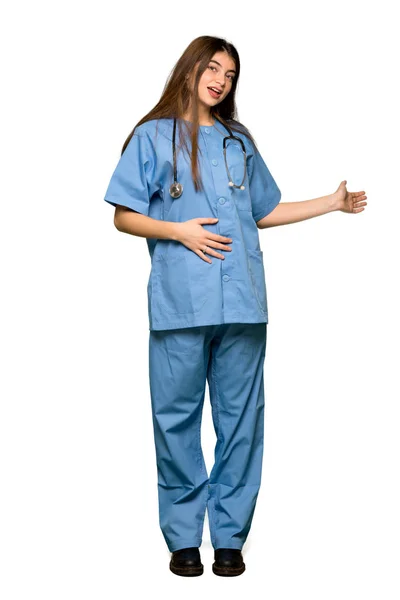 背面を指すと分離の白い背景の上に製品を提示若い看護婦のフルレングスのショット — ストック写真