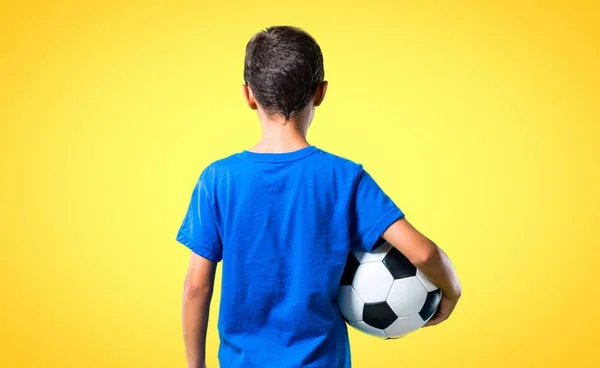 Jongen Voetballen Achterste Positie Gele Achtergrond — Stockfoto