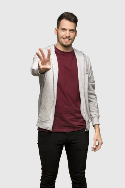 灰色の背景の上の指を使ってトレーナー幸せでカウント を持つ男 — ストック写真