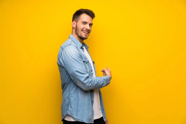 Sarı Duvar Geri Işaret Içinde Yakışıklı Adam — Stok fotoğraf