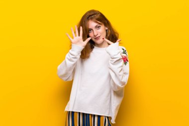 Yedi parmak ile sayma sarı duvar genç Kızıl saçlı kadın