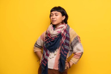 Genç hippi kadın için bir çaba yapılmış olan sırt ağrısı muzdarip sarı duvarın üzerinden