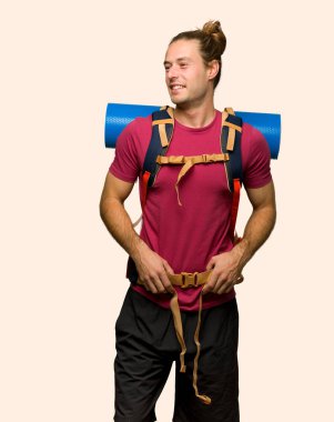 Silah, kalça ile poz ve izole arka plan üzerinde gülüyor dağ backpacker adamla uzun yürüyüşe çıkan kimse