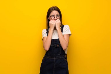 Gergin ve korkmuş ellerini ağzına koyarak sarı duvarın üzerinden kadın