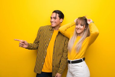 Canlı sarı arka plan üzerinde genç çift yanal pozisyonda yan parmak işaret