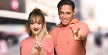 Genç çift gülümseyerek ve şehirde zafer işareti gösteren