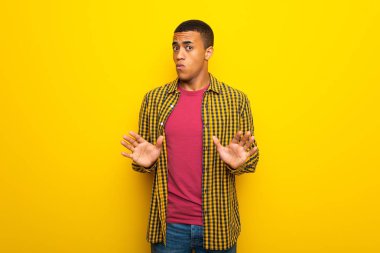 Genç afro Amerikalı adam sarı arka plan yapma dur hareketi her iki el ile Tarih