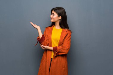 Yanına gelmek için davet için genç kız ile ceket gri duvar uzanan üzerinde eller