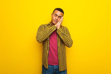 Genç afro Amerikalı adam sarı arka plan yapma uyku hareketle dorable ifade üzerinde