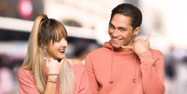 Genç çift telefon jesti yapıyor. Şehirde beni geri arayın