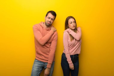 Grup için bir çaba yapılmış olan omuz ağrısı muzdarip Sarı zemin üzerine iki insan